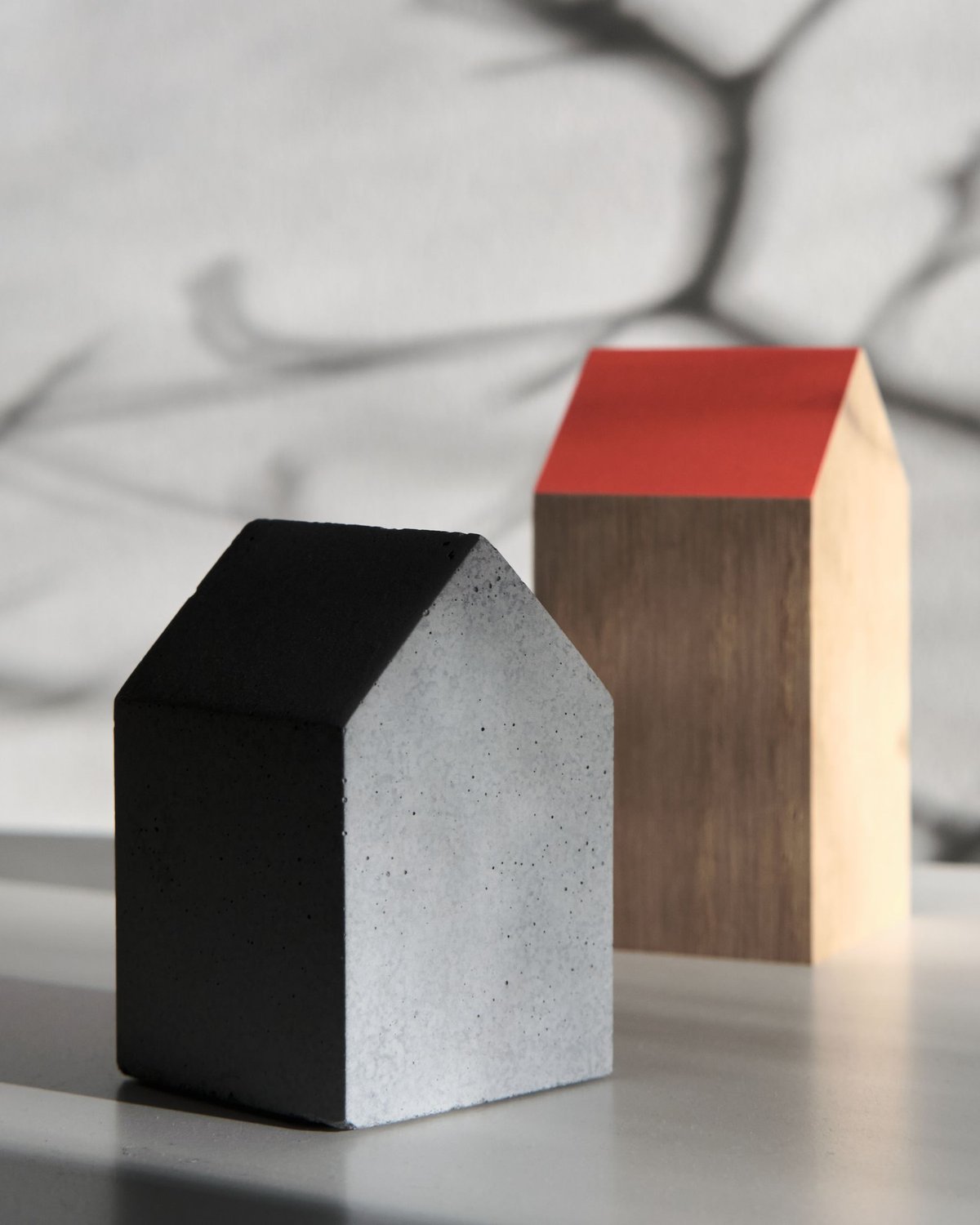 Zwei kleine Modellhäuser aus Beton und Holz, eines mit rotem Dach
